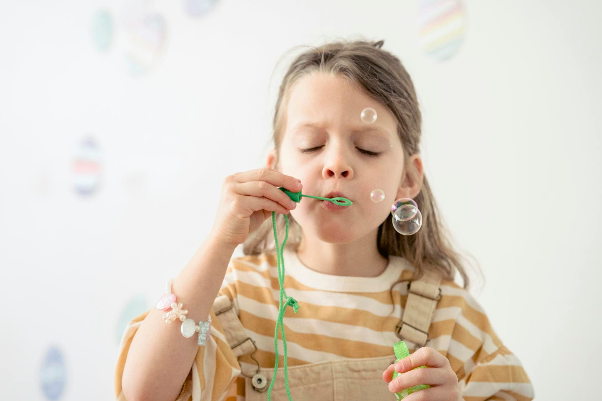 Girl blowing bubbles in room with stickers of Easter eggs